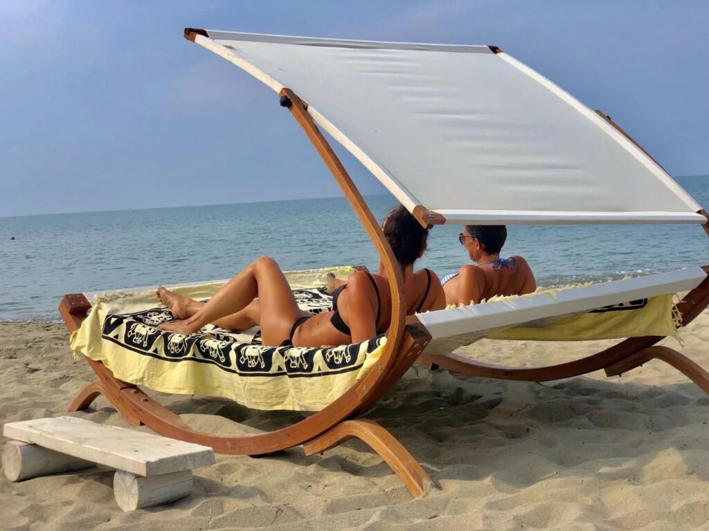 Due persone rilassate su un lettino a Kite Beach Fiumara, godendosi il sole e il mare.