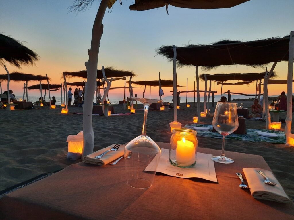 Ristorante romantico sulla spiaggia di Kite Beach Fiumara, durante il tramonto con candele e atmosfera unica.